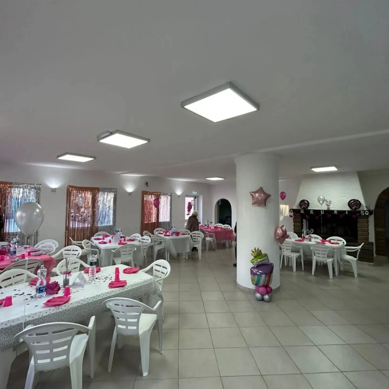 Sala interna allestita con tavoli, sedie e decorazioni rosa